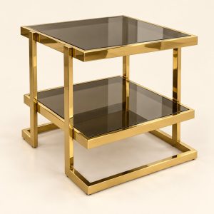 Mesa auxiliar de dos niveles Table Mezzanine con vidrio ahumado y estructura dorada pulida sobre fondo limpio